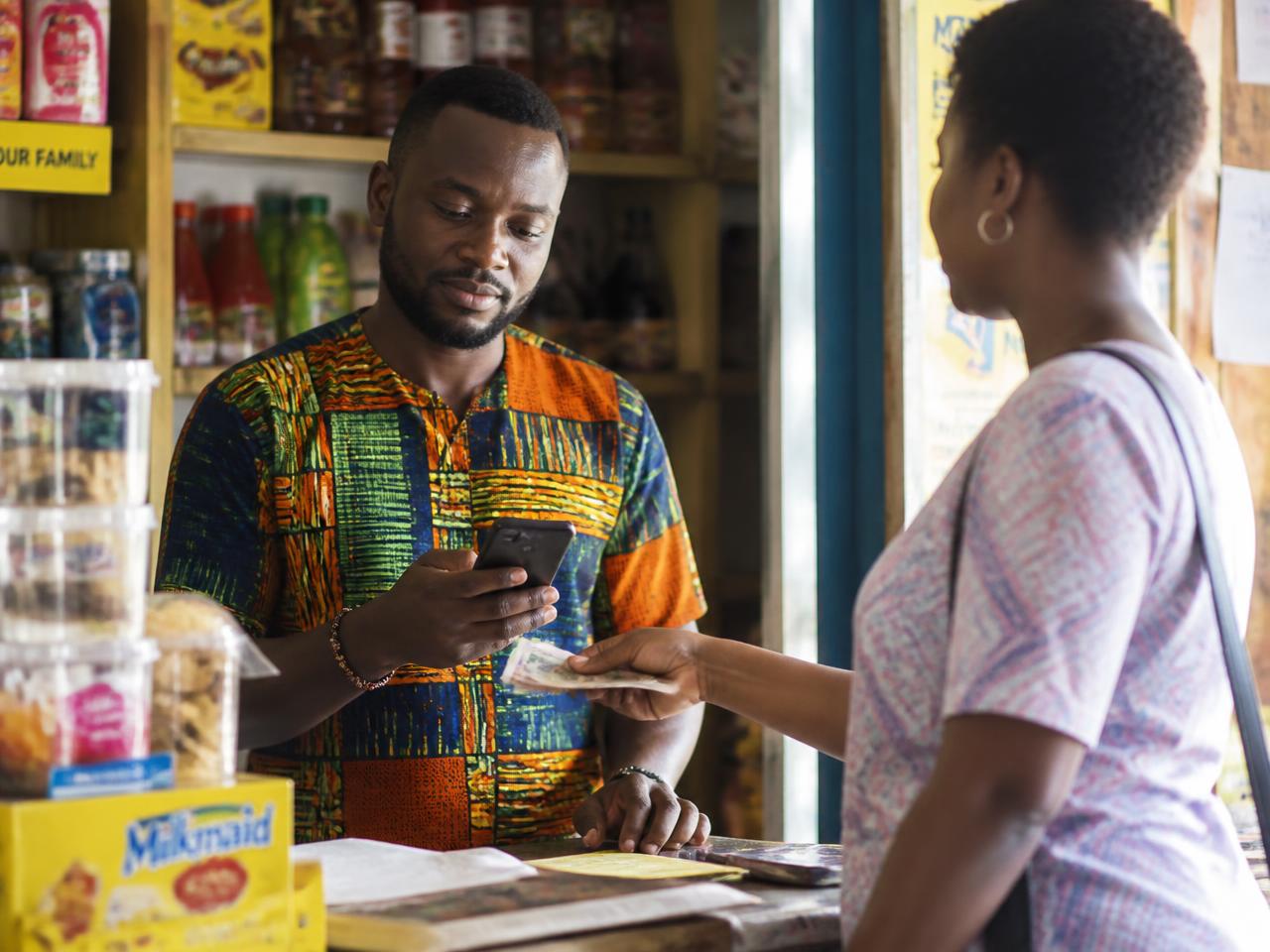 Shop owner in Accra accepting a payment on a mobile phone